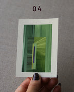 Hand holding an abstract art print sample, with a geometric style in grass green and royal blue.