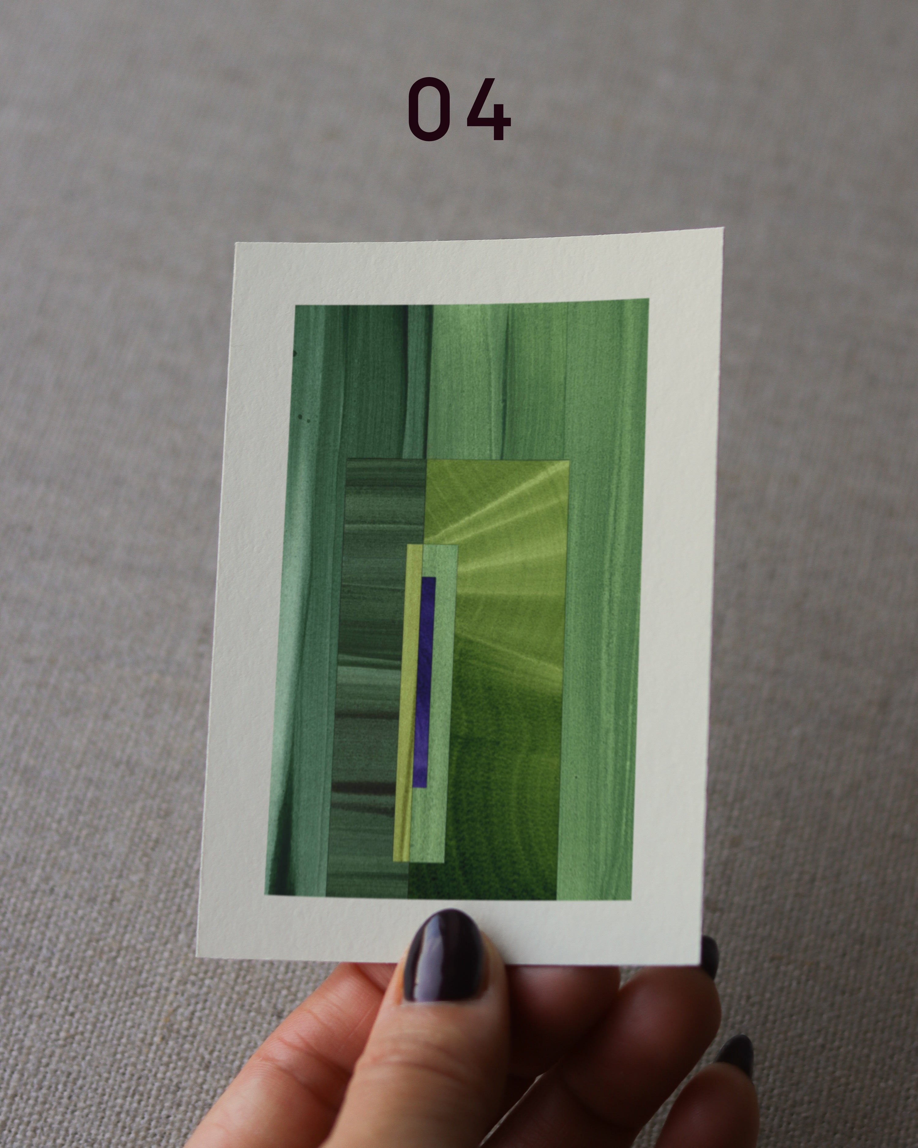 Hand holding an abstract art print sample, with a geometric style in grass green and royal blue.