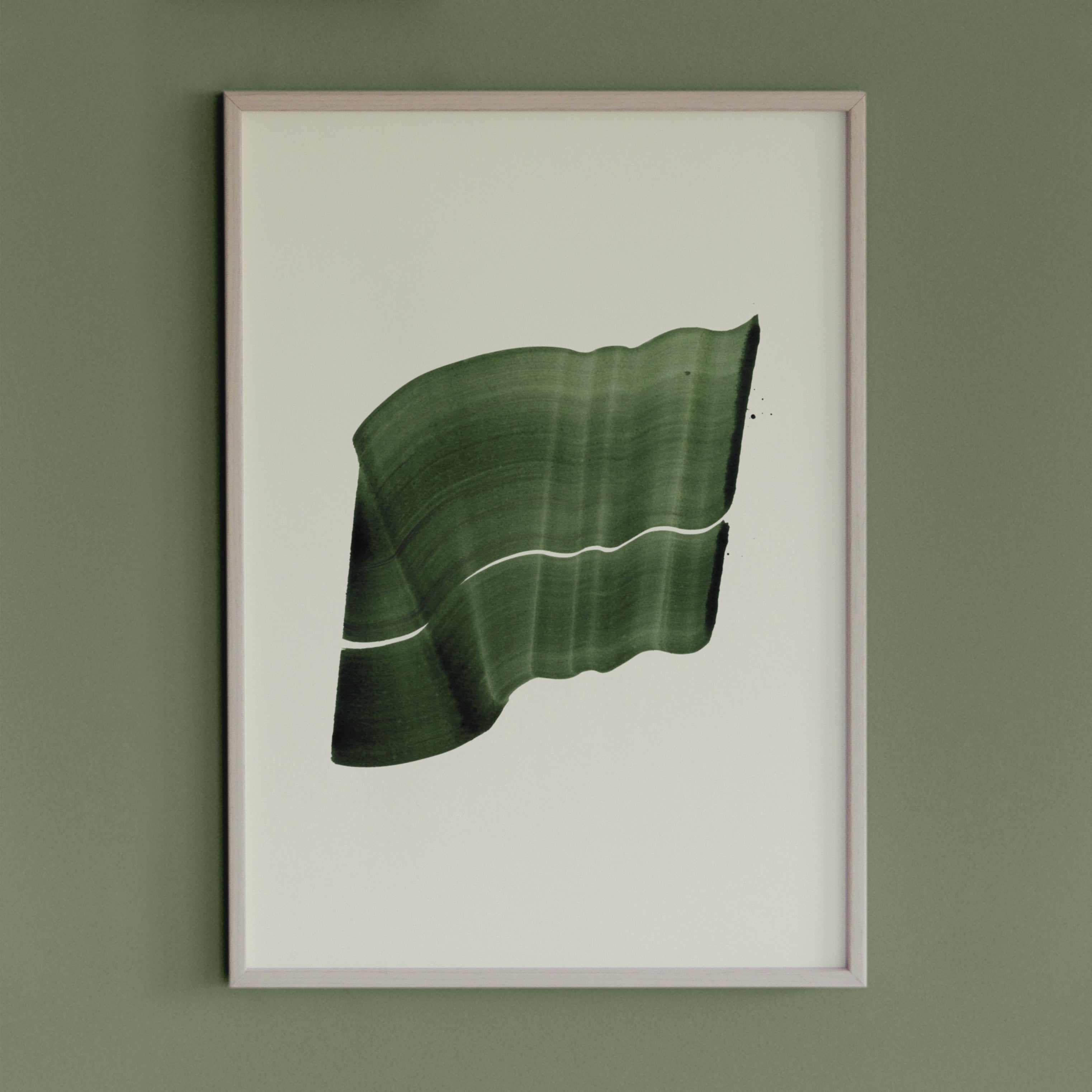 Leafy, deep green abstract artwork in a thin white oak wooden frame on a sage green wall