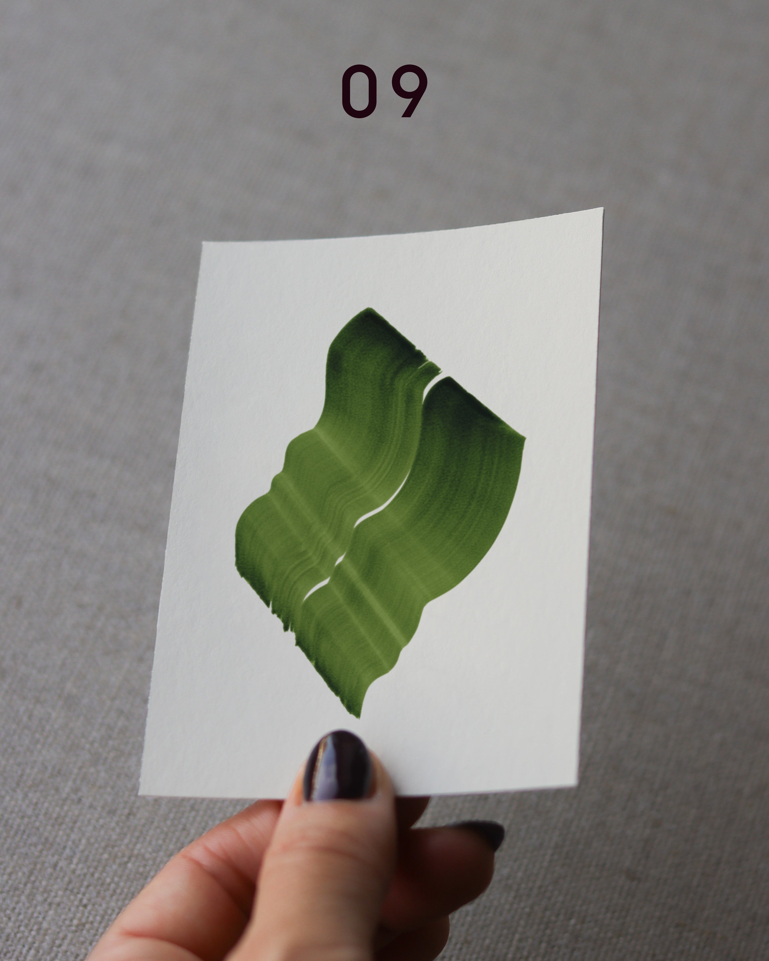 Hand holding sample of a green abstract art print with a green leaf-like design