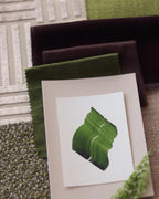 Green abstract art print sample with a green leaf-like design on a textured paint swatch with fabric swatches. Inspiration for green and pink themed interior decor.
