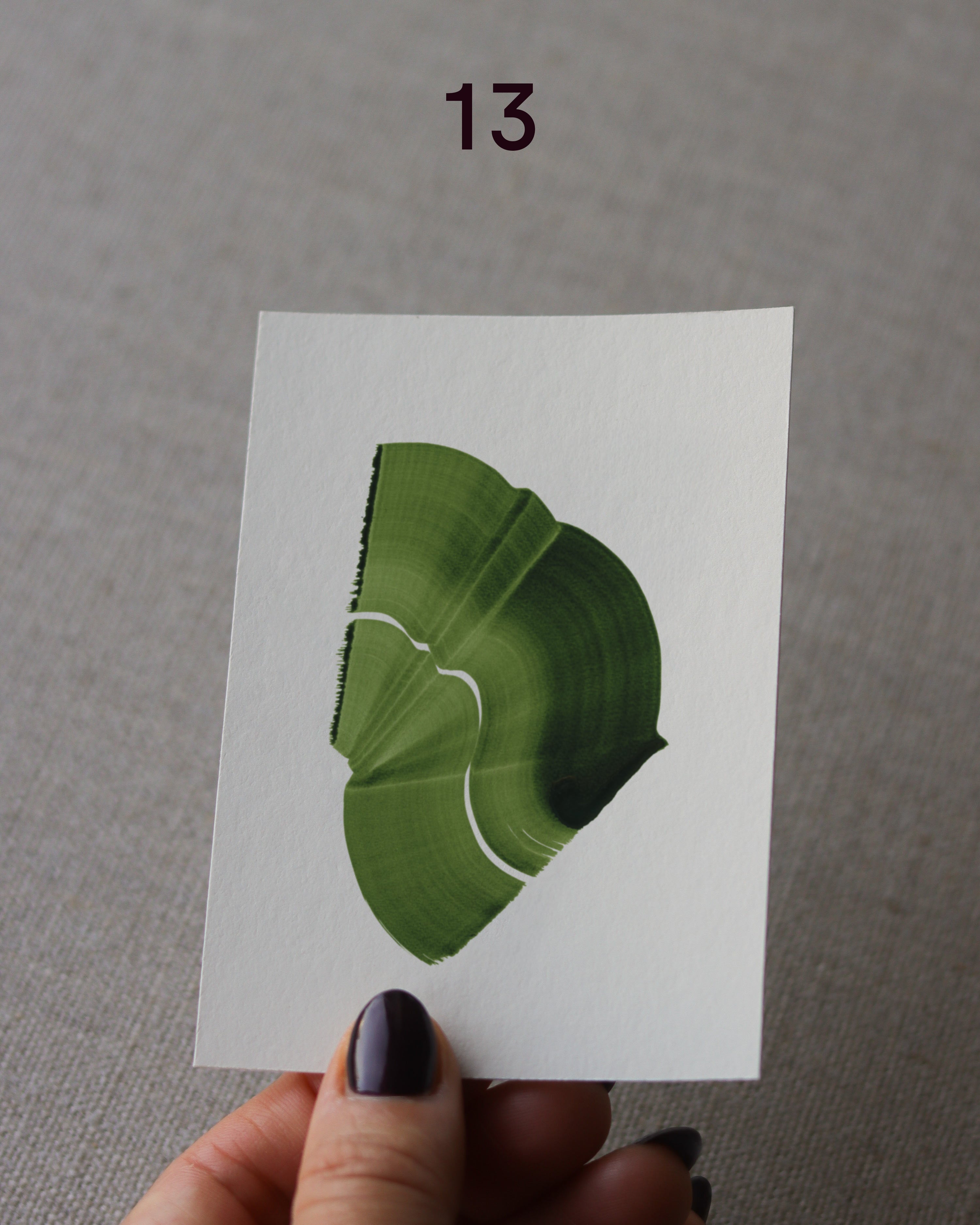 Hand holding sample of a green abstract art print with a green leaf-like design
