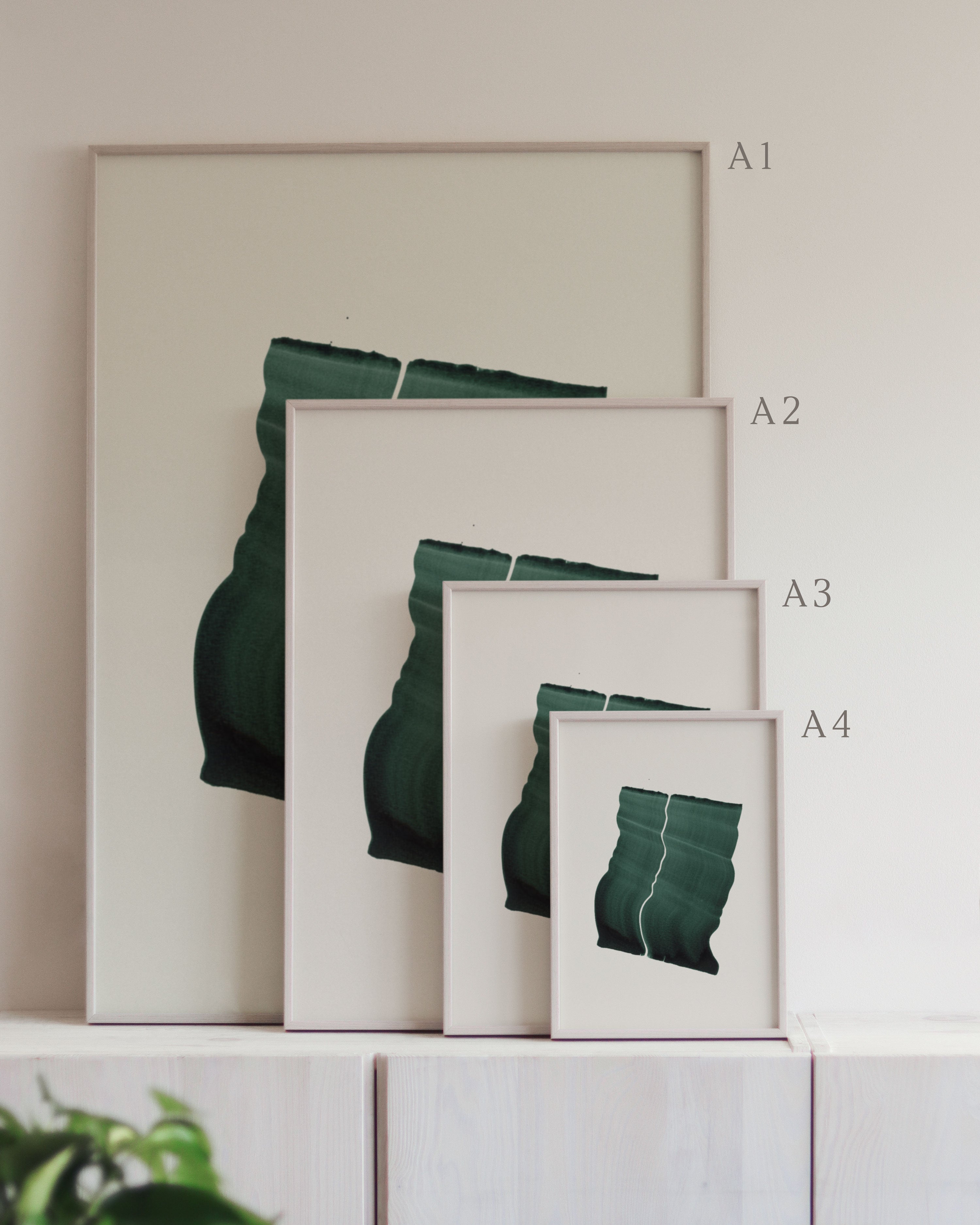 Set of framed green art prints with abstract leaf designs on a neutral background, showing in sizes A4, A3, A2 and A1