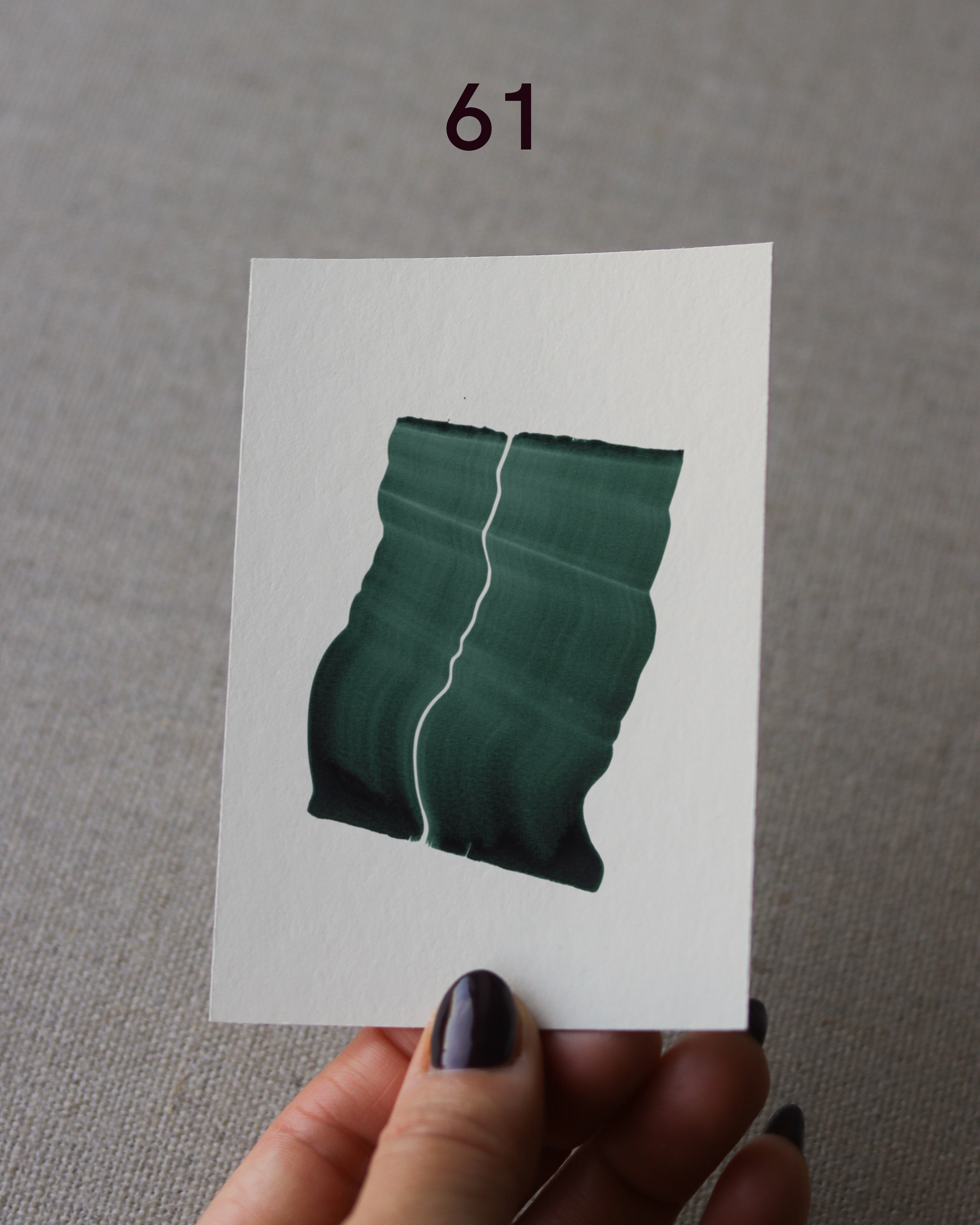 Hand holding sample of a green abstract art print with a green leaf-like design