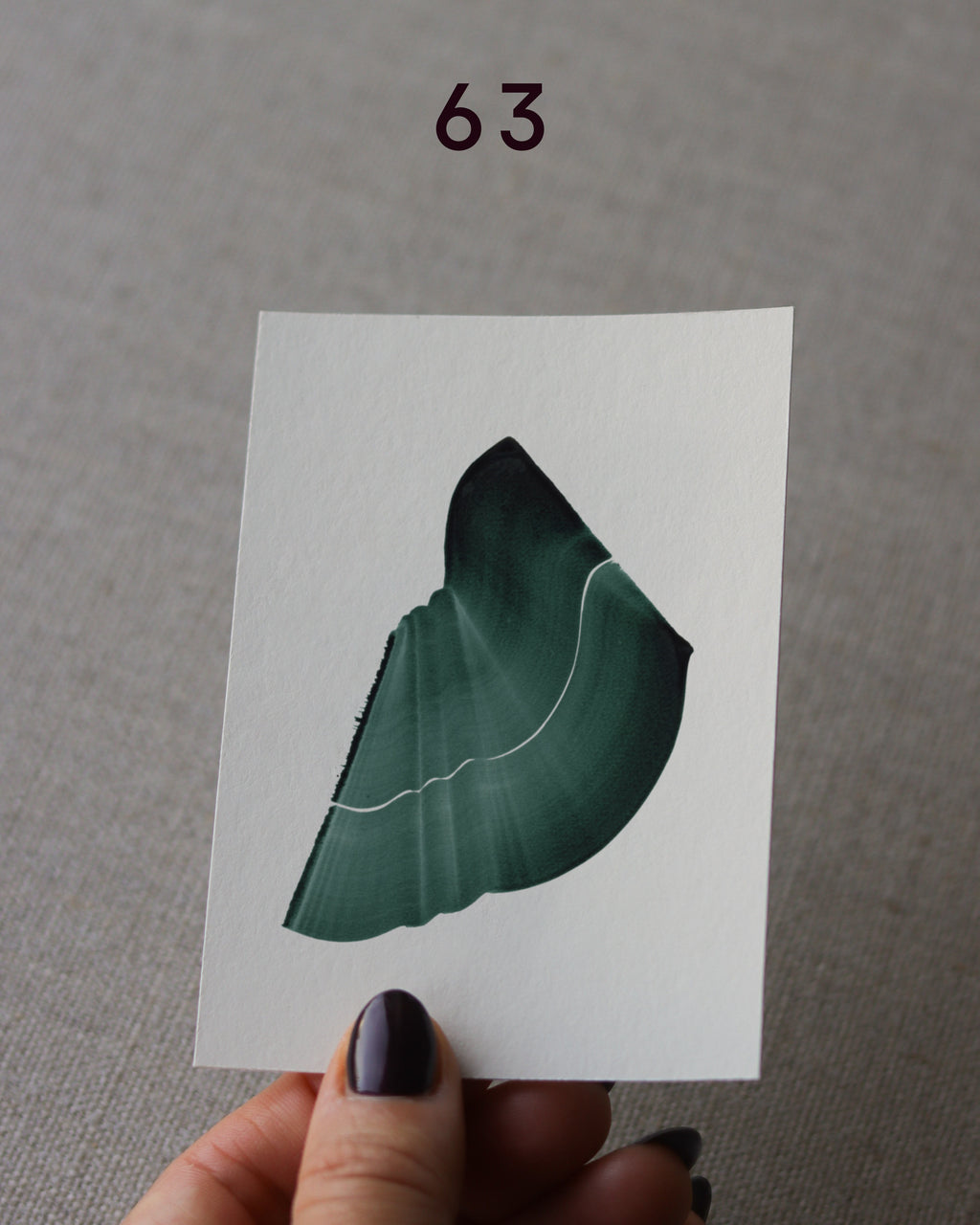 Hand holding sample of a green abstract art print with a green leaf-like design