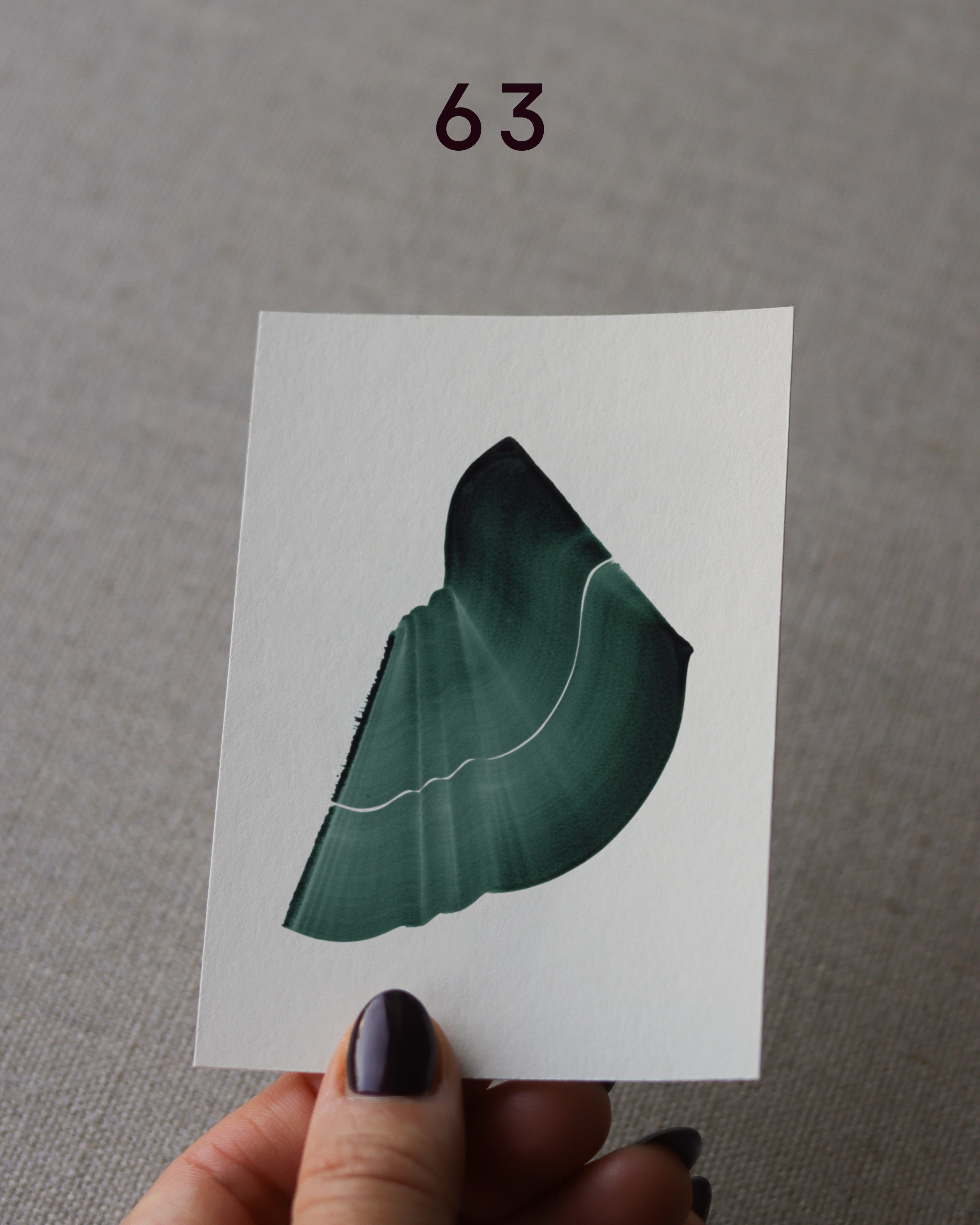 Hand holding sample of a green abstract art print with a green leaf-like design