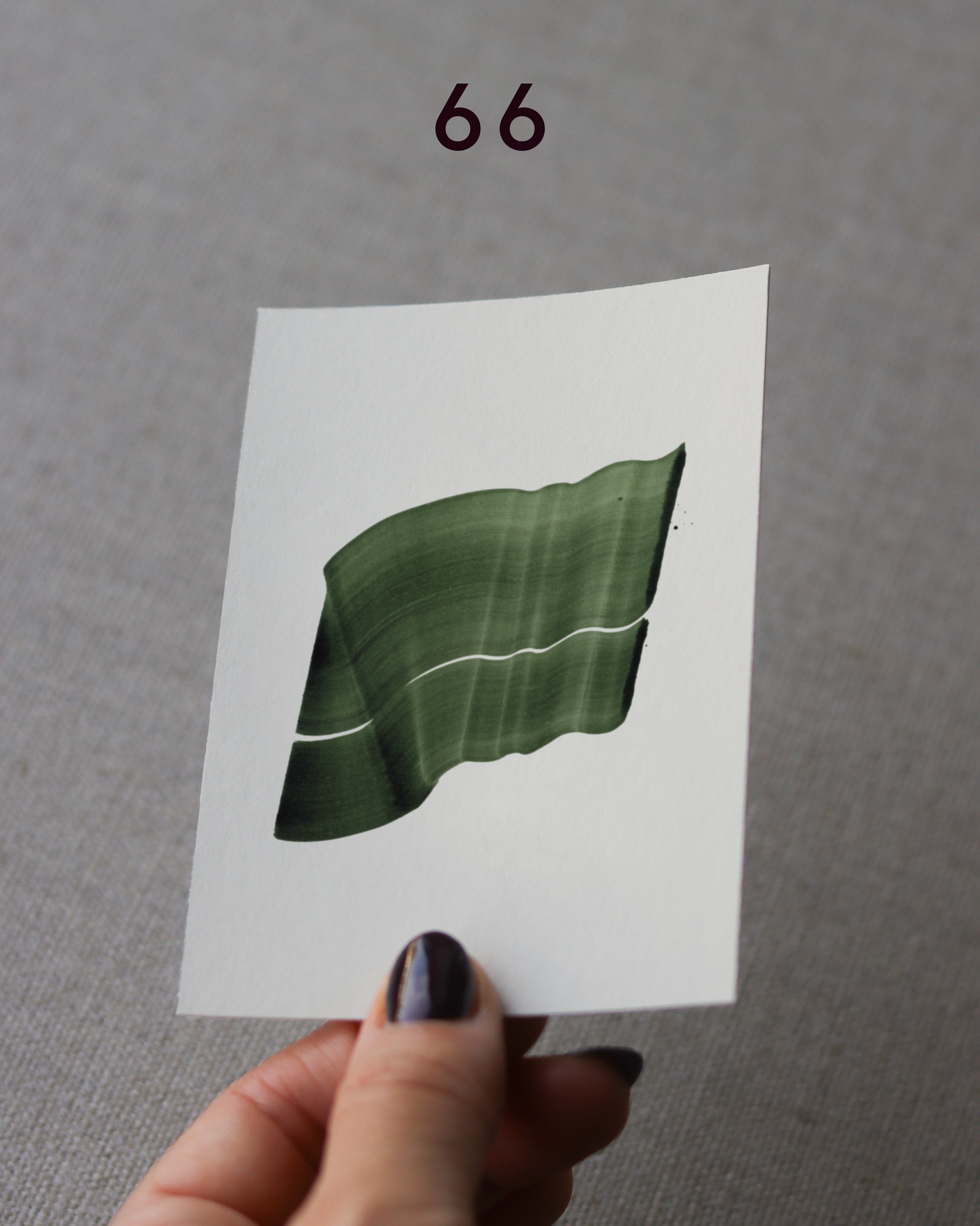 Hand holding sample of a green abstract art print with a green leaf-like design