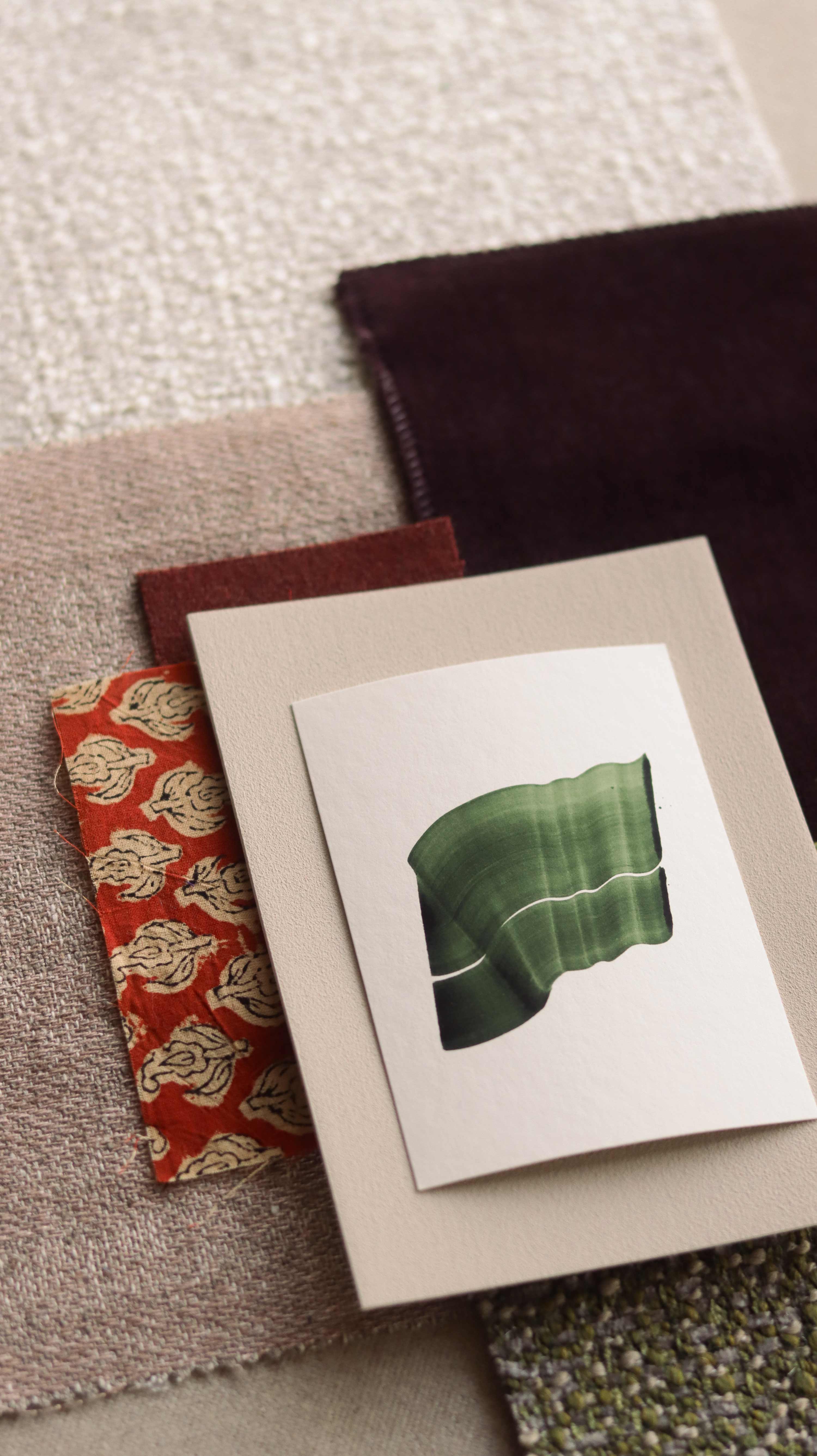 Green abstract art print sample with a green leaf-like design on a textured paint swatch with fabric swatches. Inspiration for blush pink, rust orange and burgundy themed interior decor.