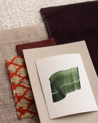 Green abstract art print sample with a green leaf-like design on a textured paint swatch with fabric swatches. Inspiration for green and pink themed interior decor.