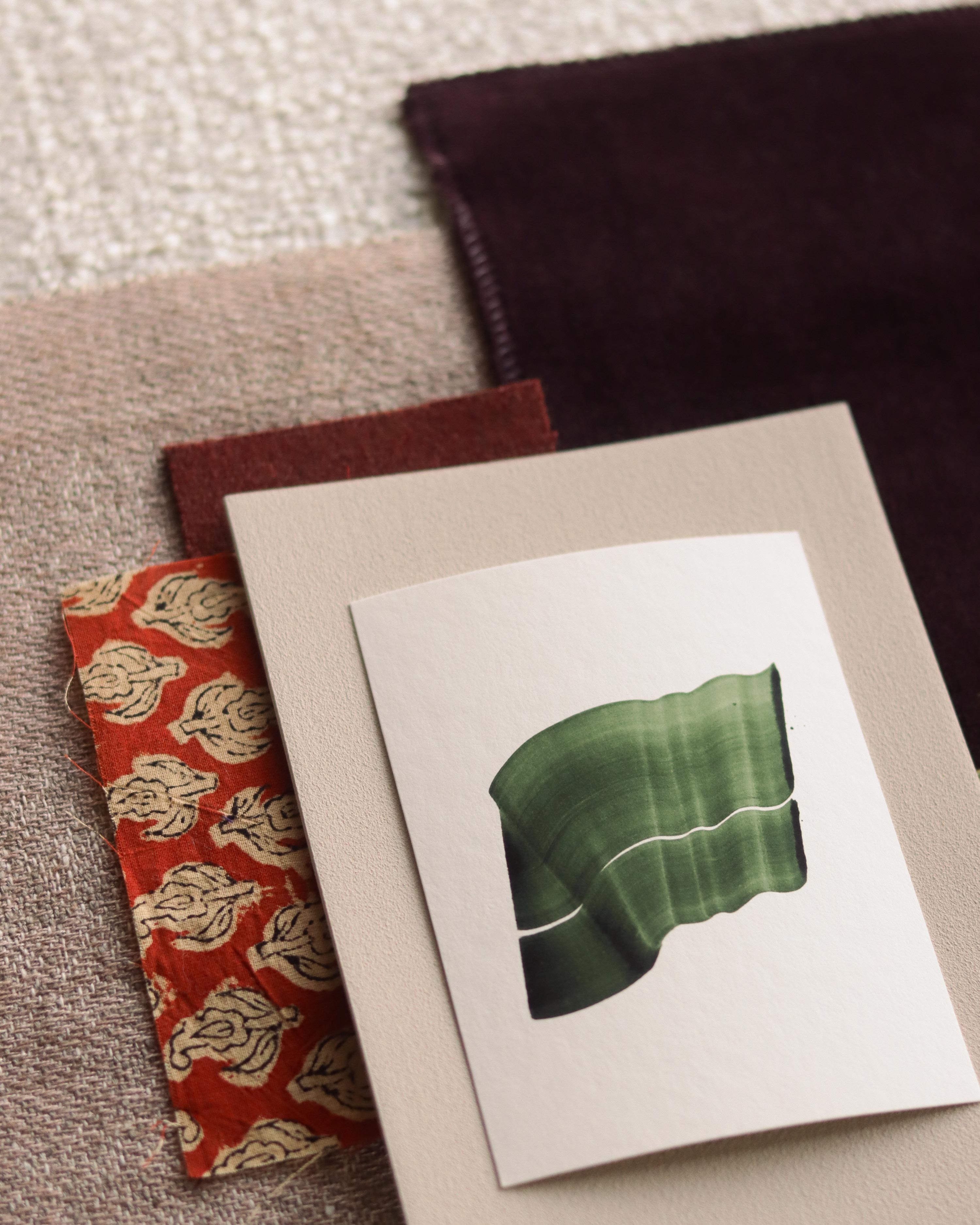 Green abstract art print sample with a green leaf-like design on a textured paint swatch with fabric swatches. Inspiration for green and pink themed interior decor.