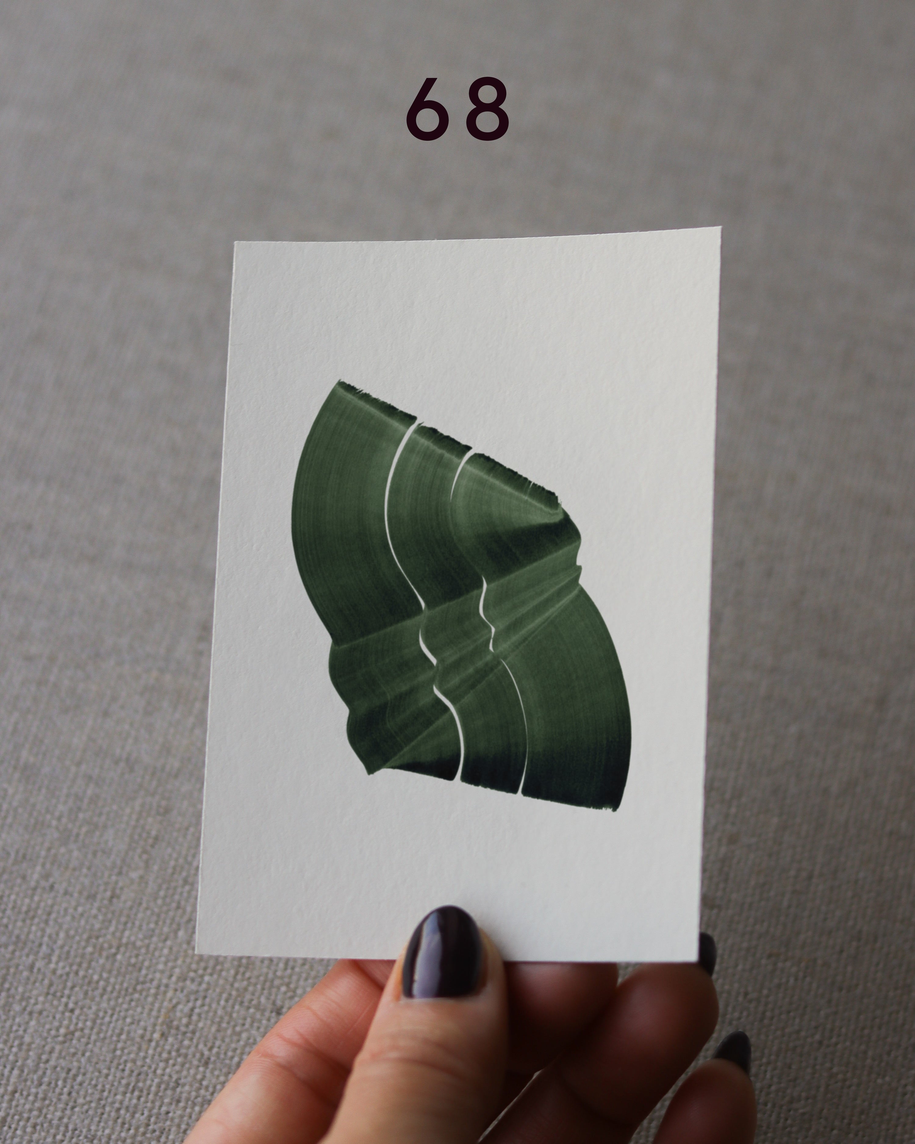 Hand holding sample of a green abstract art print with a green leaf-like design