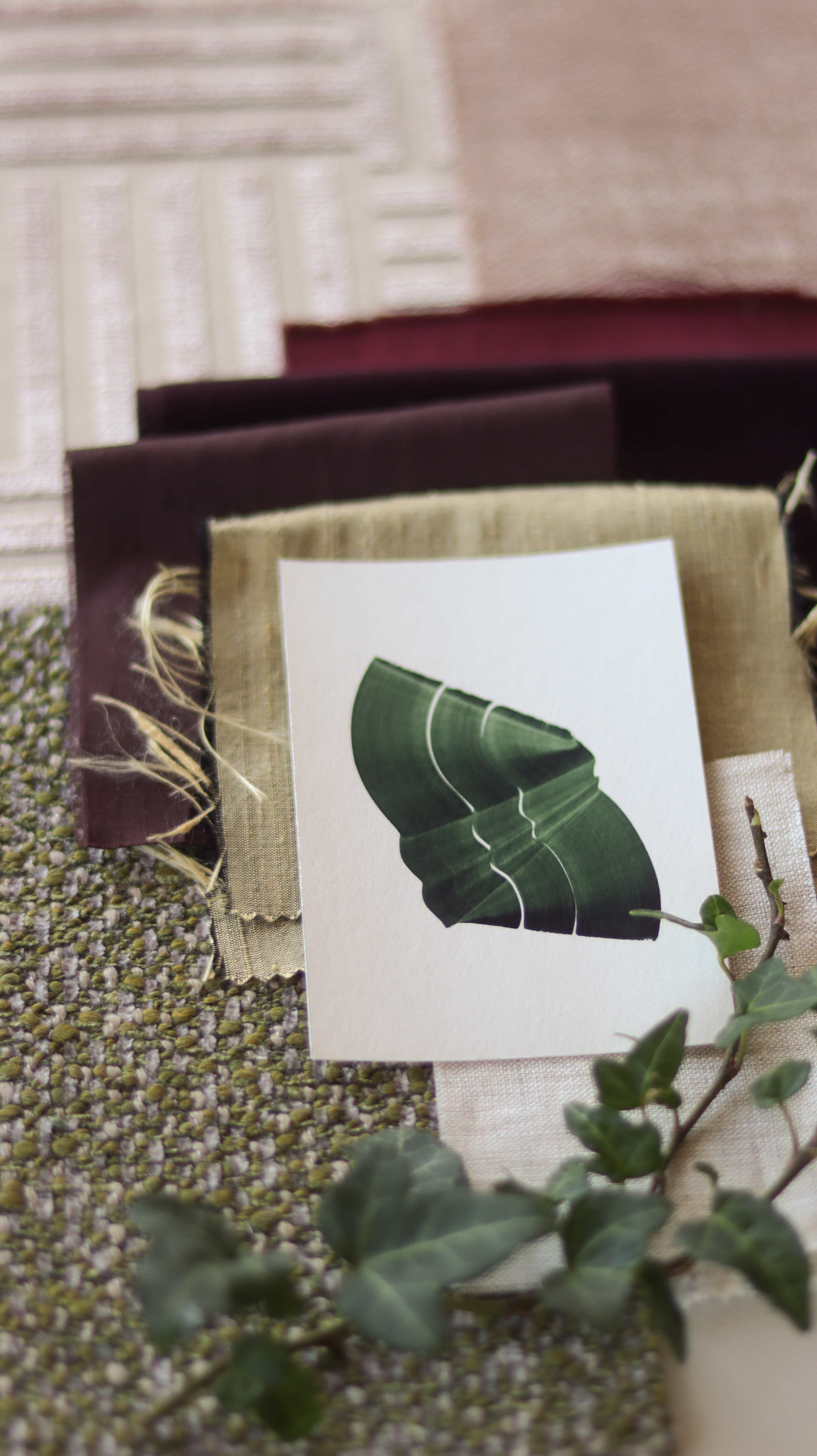 Green abstract art print sample with a green leaf-like design on fabric swatches. Inspiration for pink, red and muted earthy toned themed interior decor.