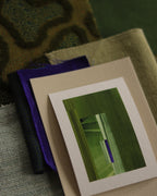 Small geometric abstract art print sample with moss green, sage green and blue colours, laying on top of fabric swatches for green interiors colour inspiration.