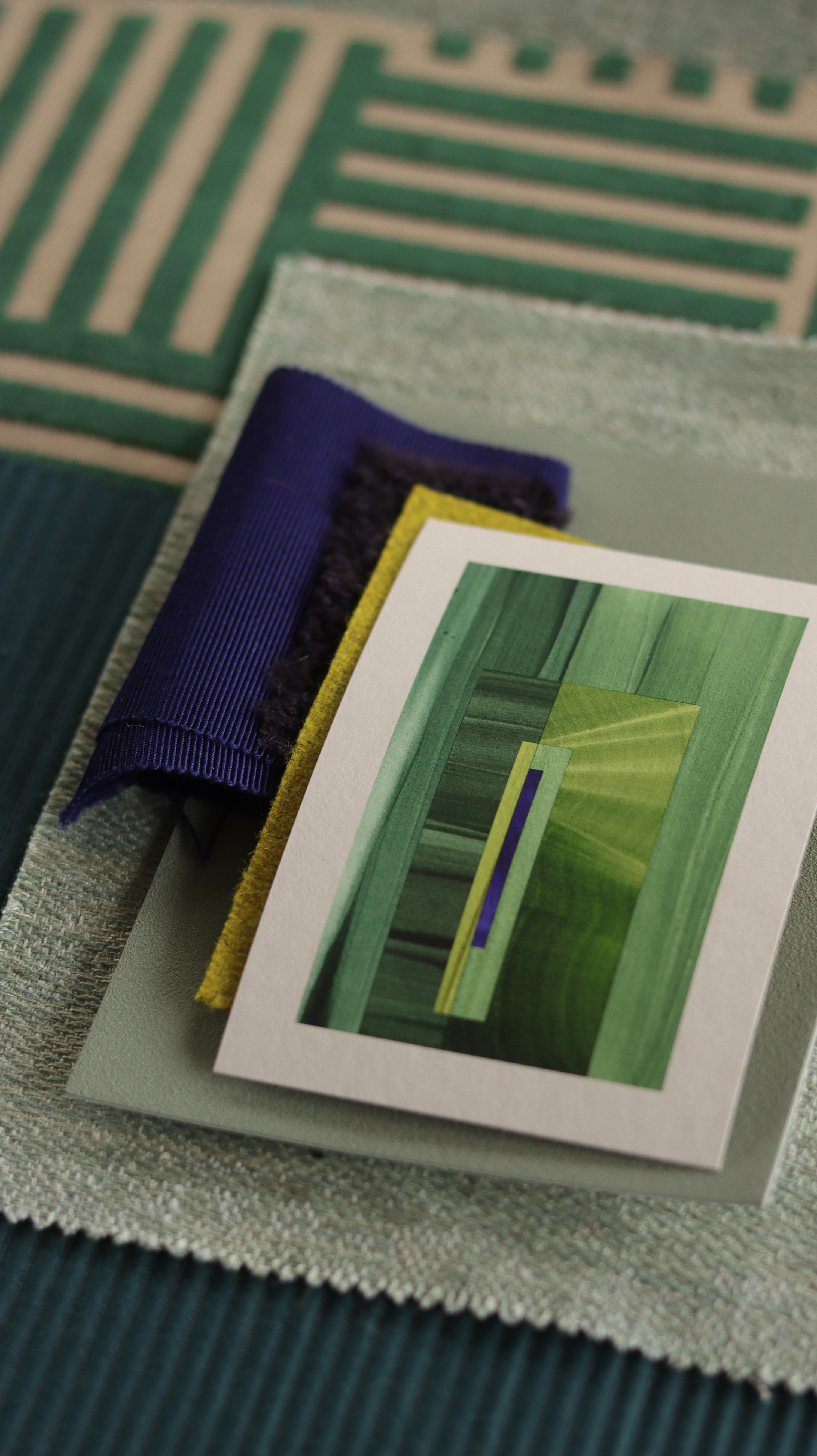 Small abstract art print sample with forest green and blue colours, laying on top of fabric swatches for green interiors colour inspiration.