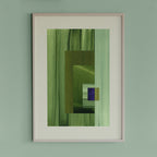 Framed geometric abstract art piece with grass green, mint and blue colours on a light green wall.