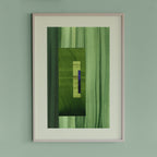 Framed geometric abstract art piece with grass green and blue colours on a light green wall.