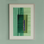 Framed geometric abstract art piece with turquoise, mint green and blue colours on a light green wall.