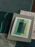 Small abstract art print sample with turquoise, forest green and blue colours, laying on top of fabric swatches for teal interiors colour inspiration.
