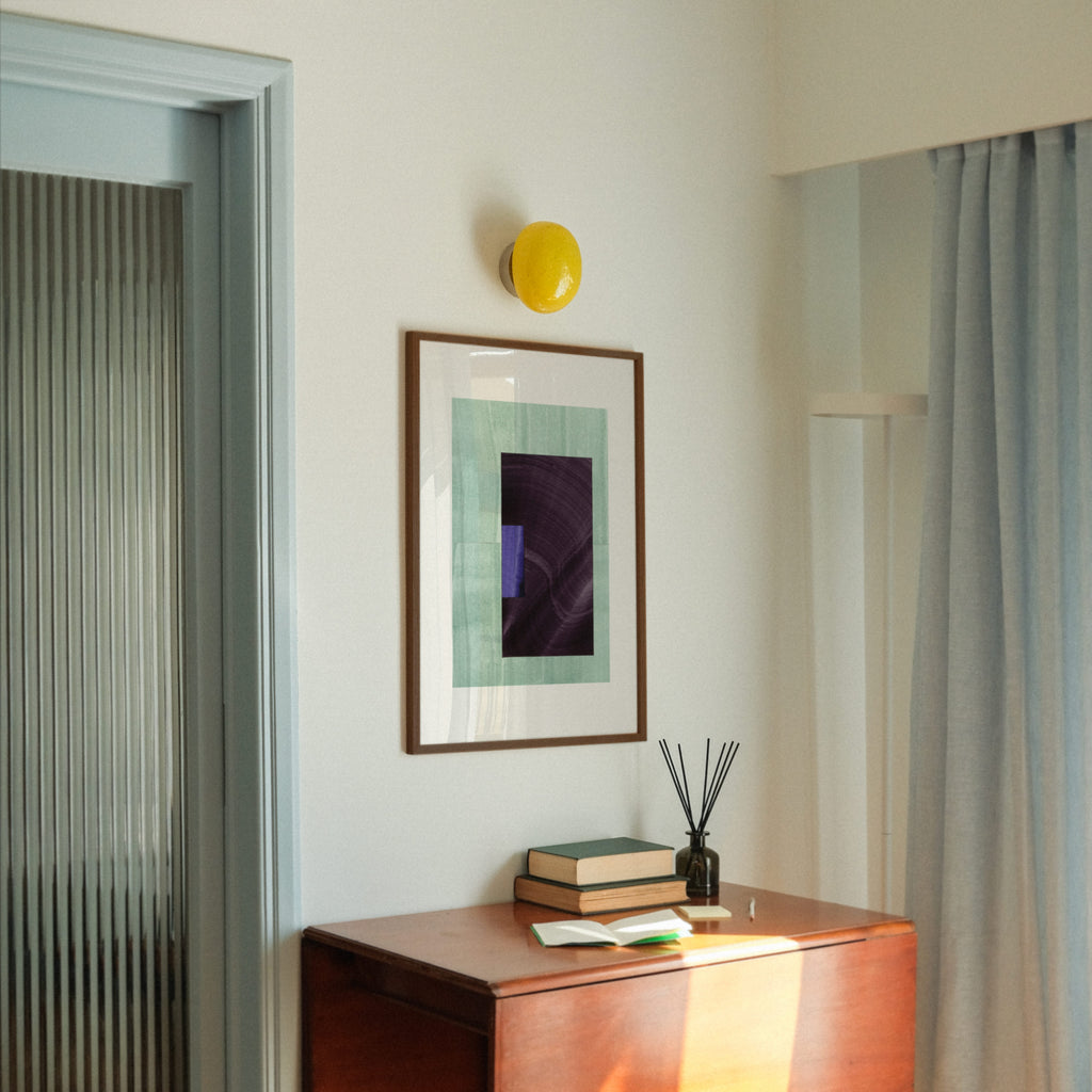 Geometric abstract art with turquoise, eggplant purple and blue colours, in a walnut frame, hung in a midcentury modern, minimal living room interior.