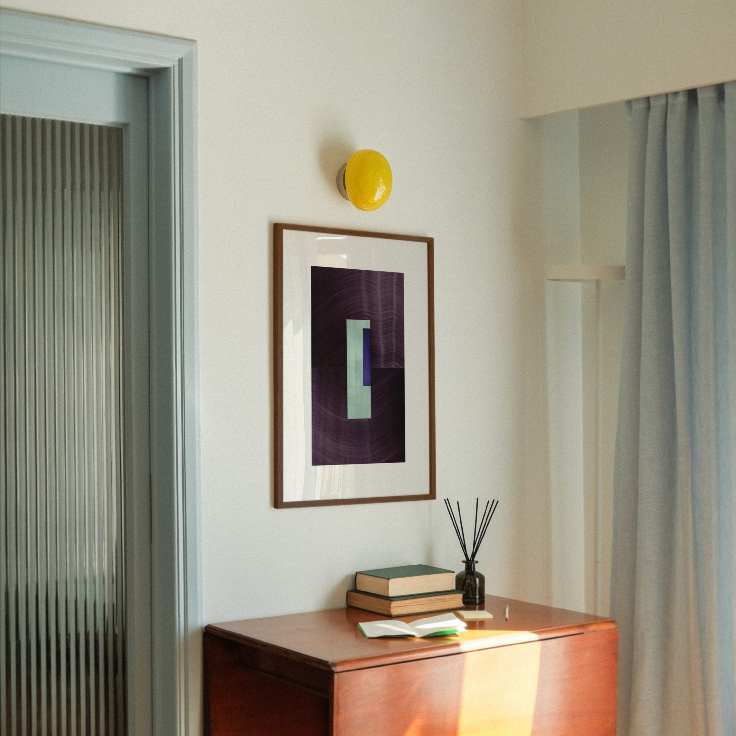 Geometric abstract art with eggplant purple, turquoise and blue colours, in a walnut frame, hung in a midcentury modern, minimal living room interior.
