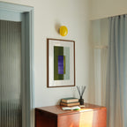 Geometric abstract art with olive green and blue colours, in a walnut frame, hung in a midcentury modern, minimal living room interior.