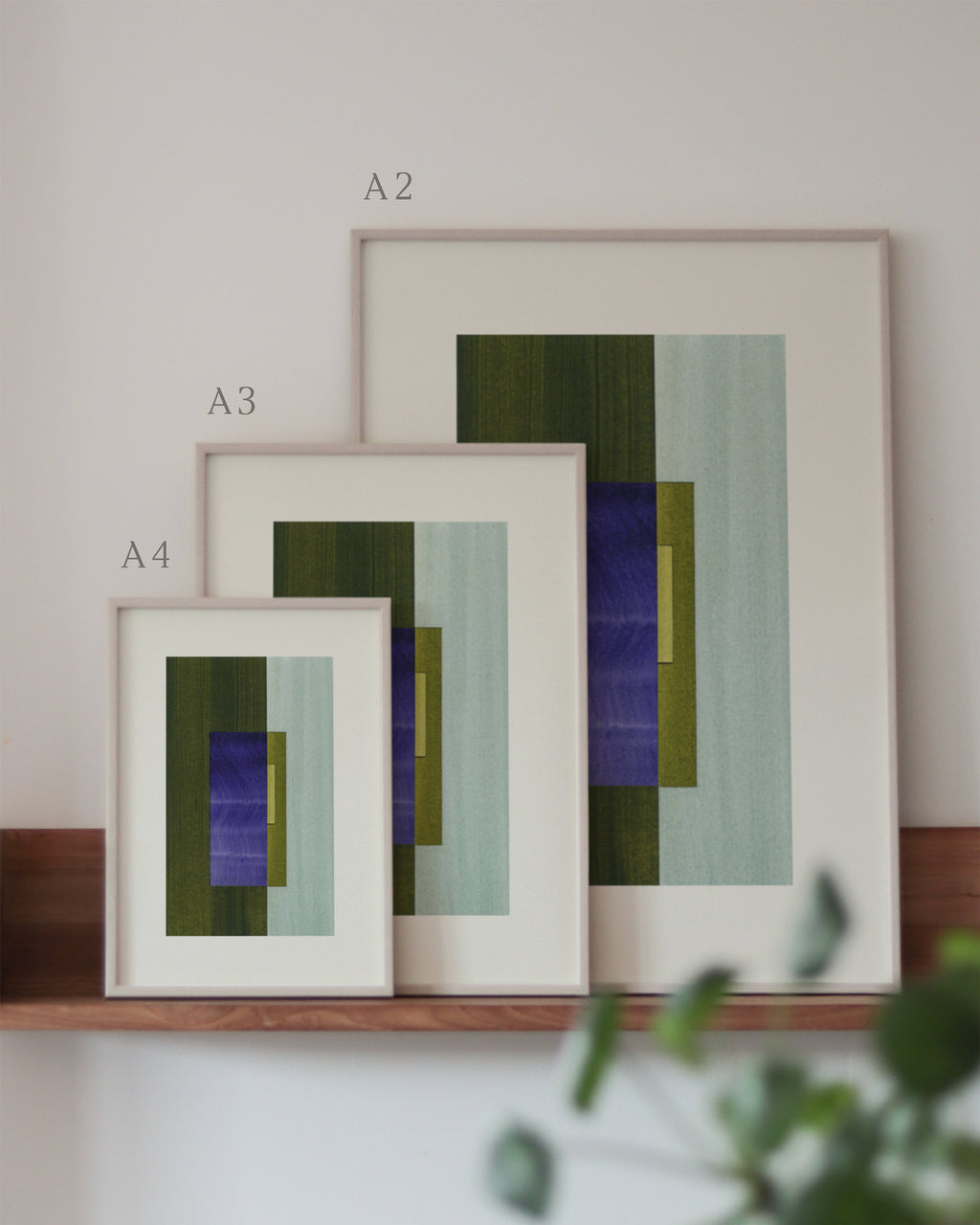 Set of green and blue framed geometric abstract art prints on a neutral background, showing in sizes A4, A3, and A2