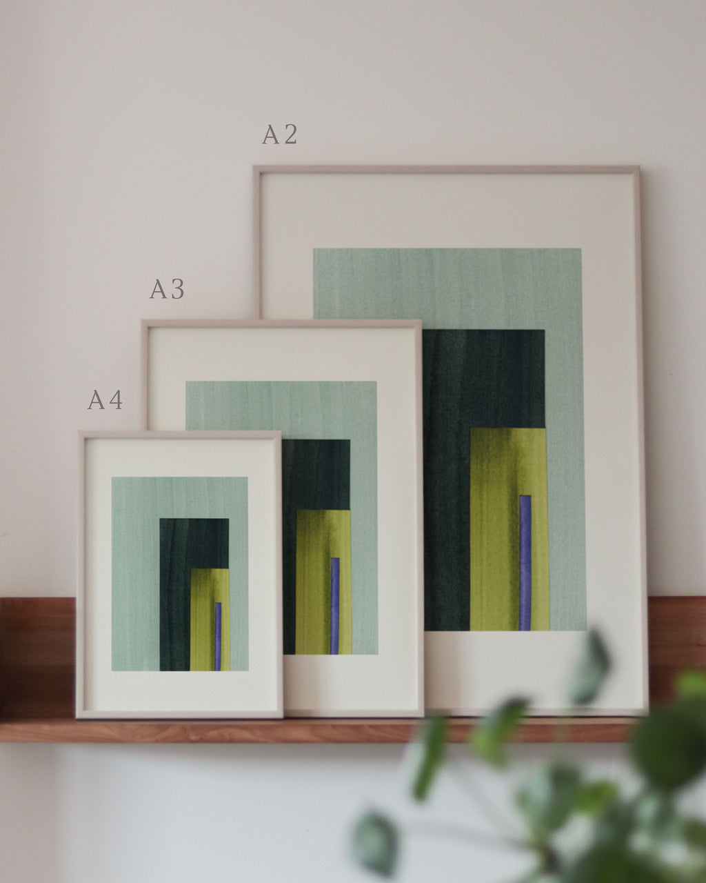 Set of turquoise, yellow and blue framed geometric abstract art prints on a neutral background, showing in sizes A4, A3, and A2