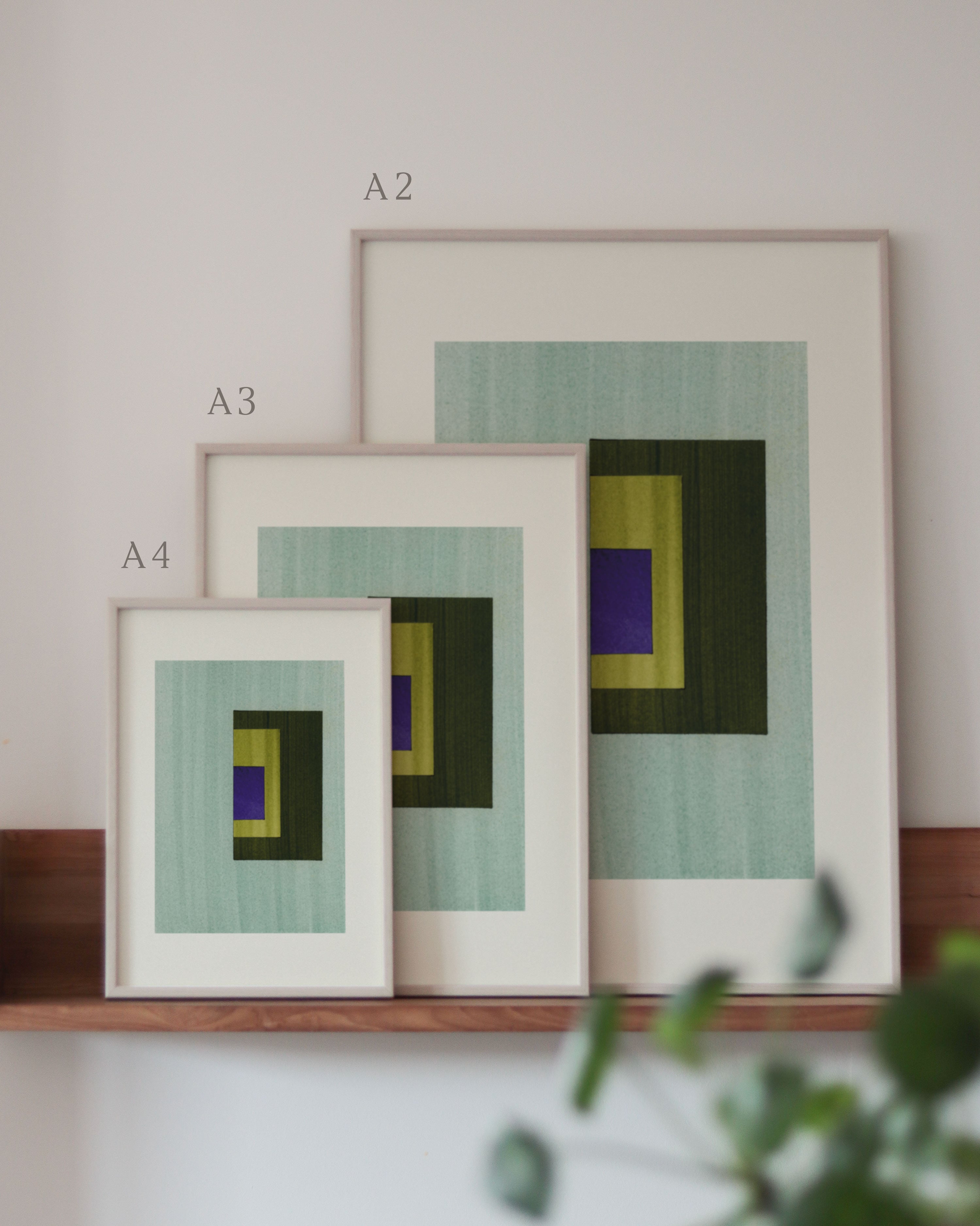 Set of turquoise, green and blue framed geometric abstract art prints on a neutral background, showing in sizes A4, A3, and A2