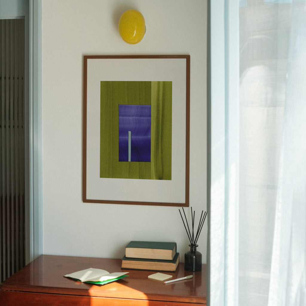 Geometric abstract art with green and blue colours, in a walnut frame, hung in a midcentury modern, minimal living room interior.