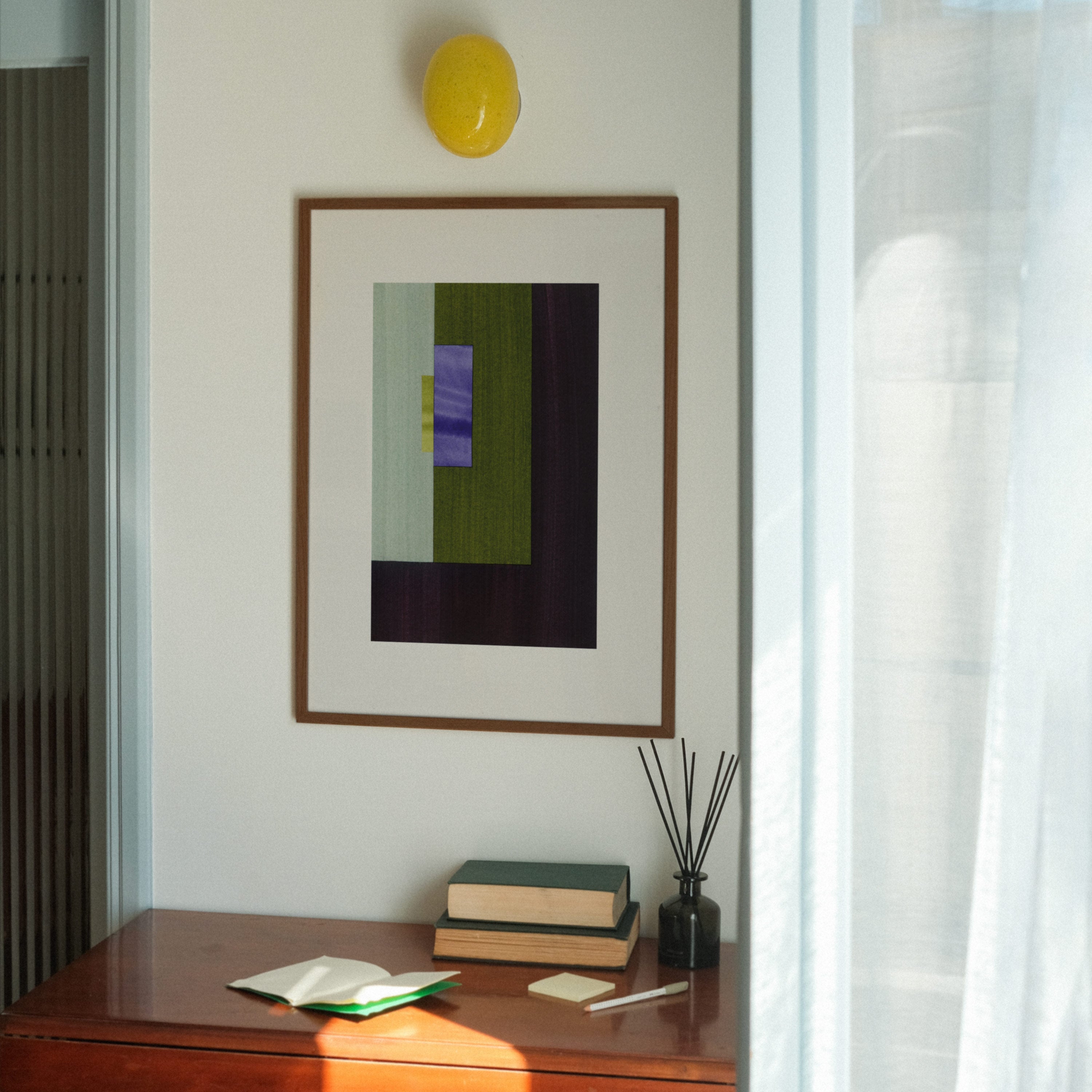 Geometric abstract art with deep brown, green and blue colours, in a walnut frame, hung in a midcentury modern, minimal living room interior.
