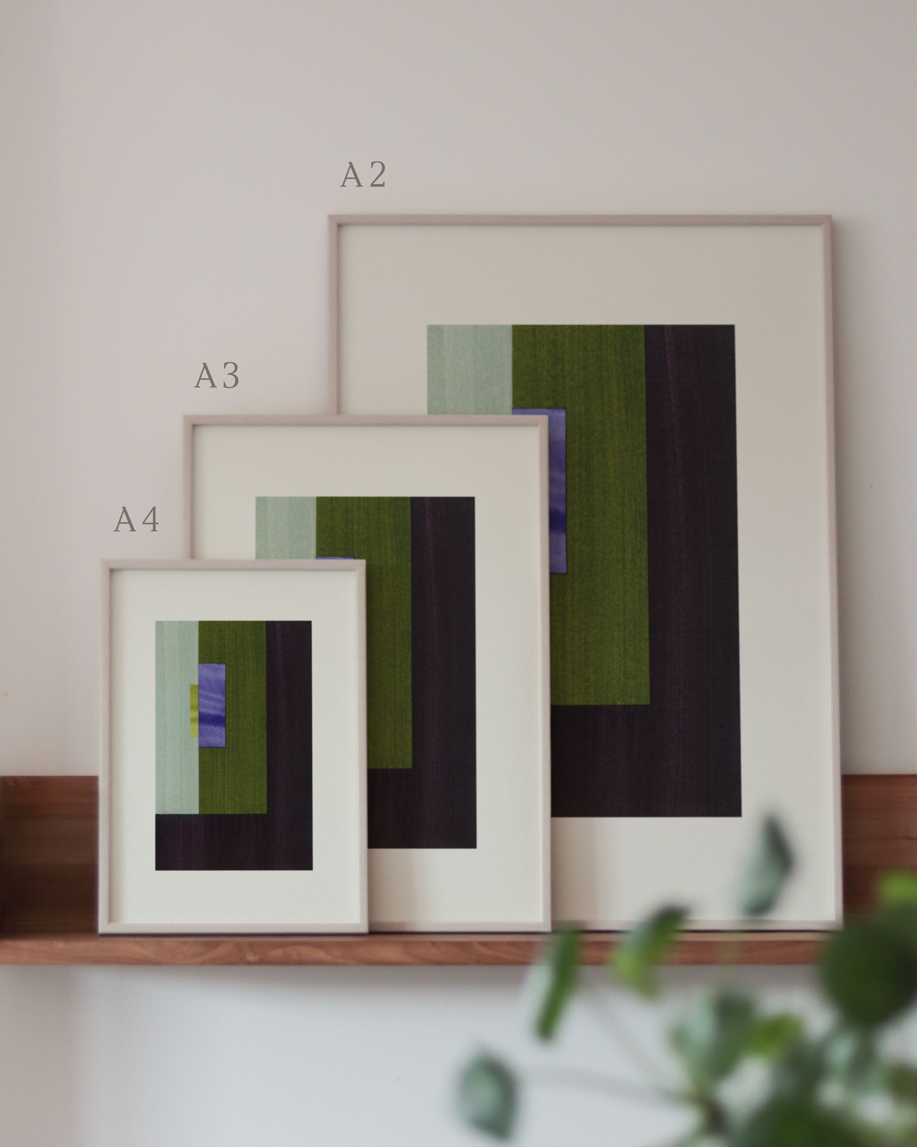 Set of green, brown and blue framed geometric abstract art prints on a neutral background, showing in sizes A4, A3, and A2