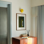 Geometric abstract art with olive green and blue colours, in a walnut frame, hung in a midcentury modern, minimal living room interior.