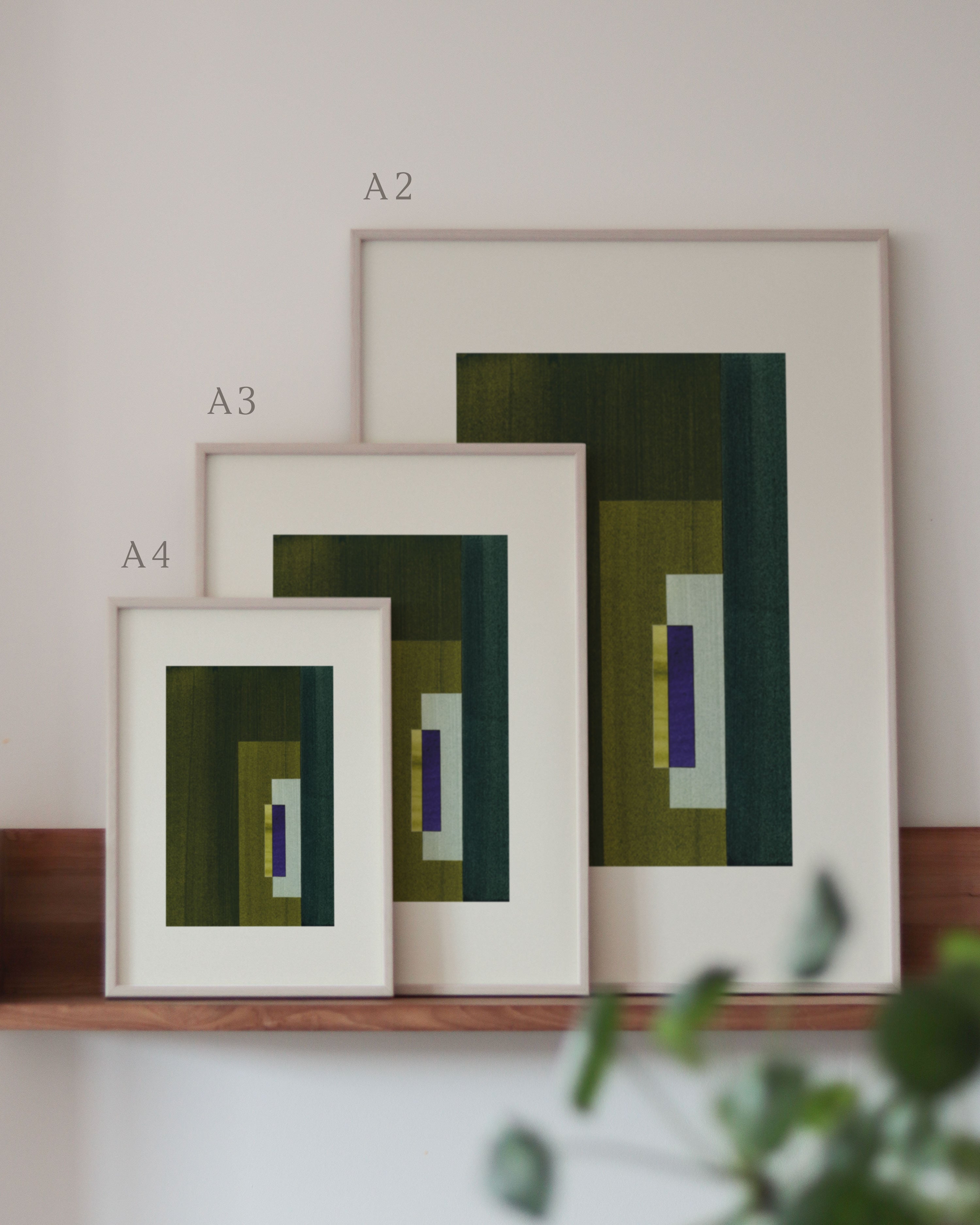 Set of green and blue framed geometric abstract art prints on a neutral background, showing in sizes A4, A3, and A2